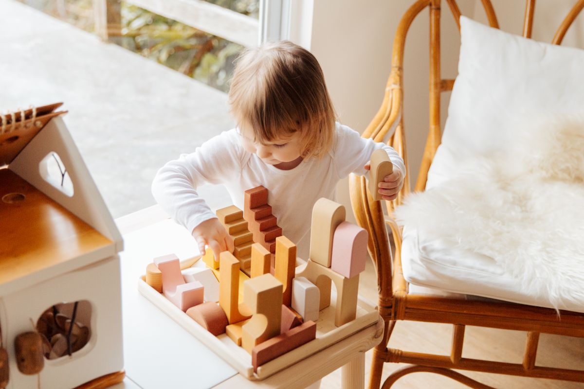 A child absorbed in playing with wooden blocks in a sunlit room